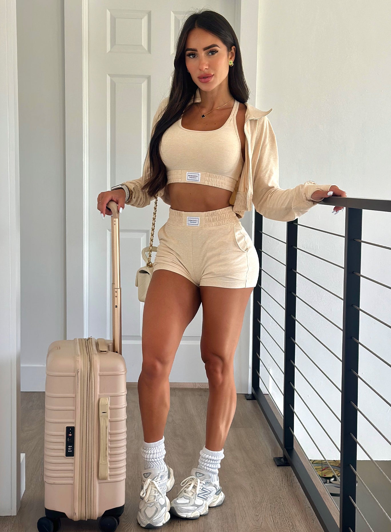 A full body view of our model wearing our Cloud Lounge Bra in vanilla with a suitcase to her right side