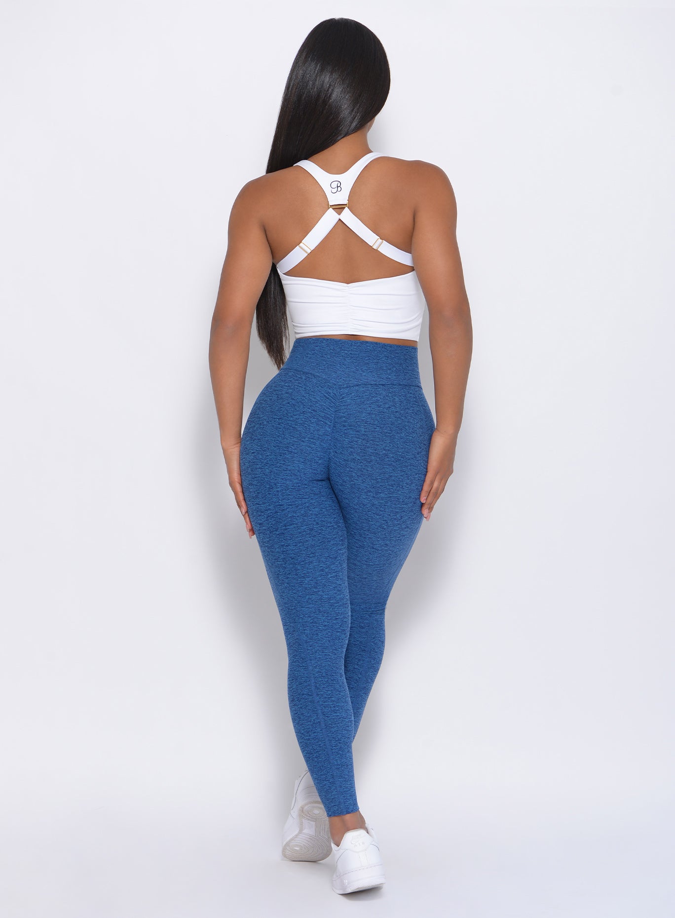 Back view of the model wearing our Brazilian contour leggings in ocean color and a white top