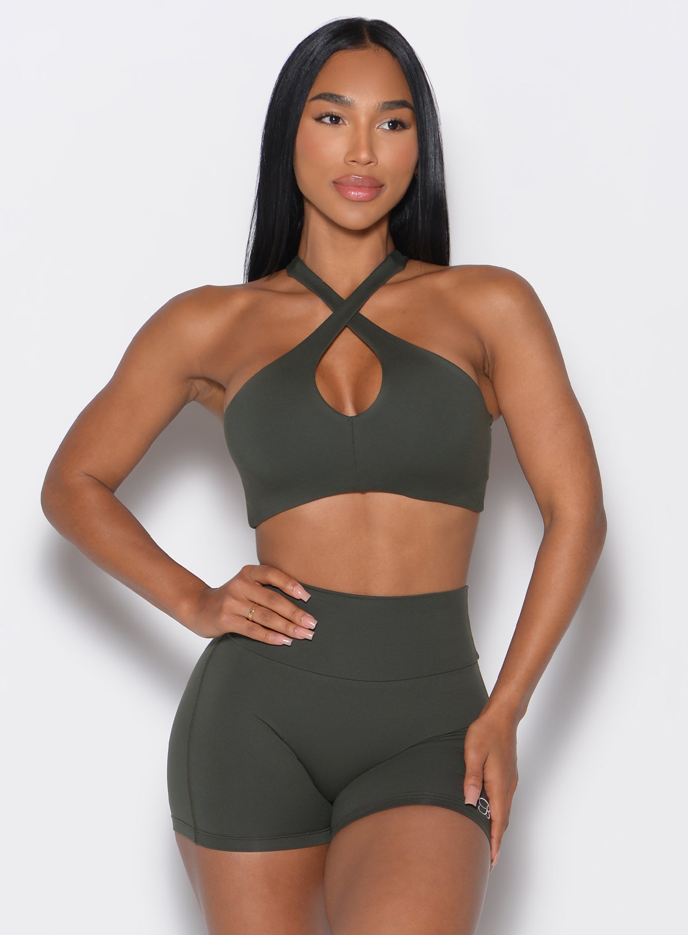 front profile view of a model wearing our Cross Over Halter Bra and the matching leggings in Deep Ivy color