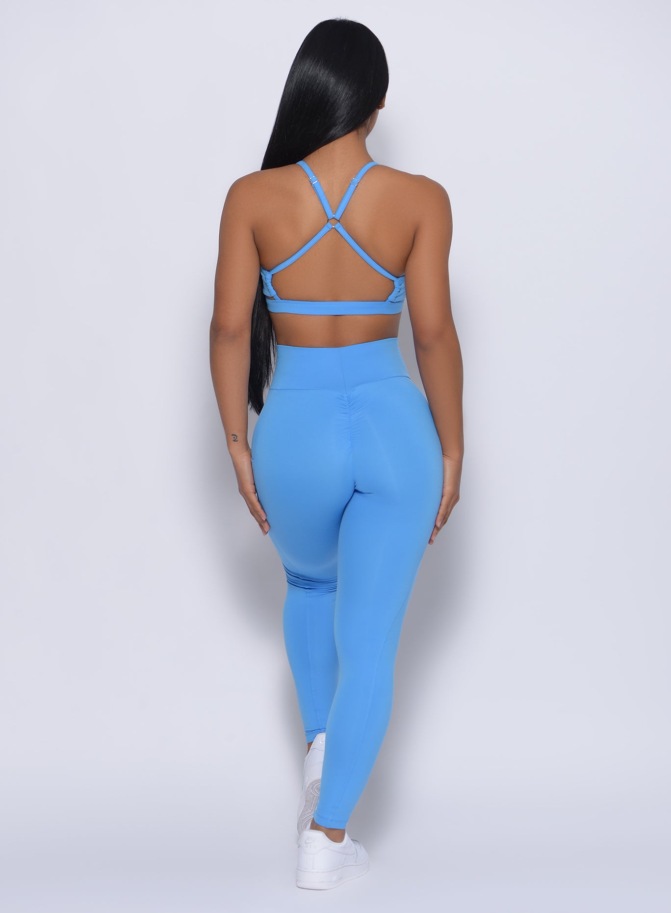 Back profile view of the model in our curves leggings in blazing blue color and a matching bra