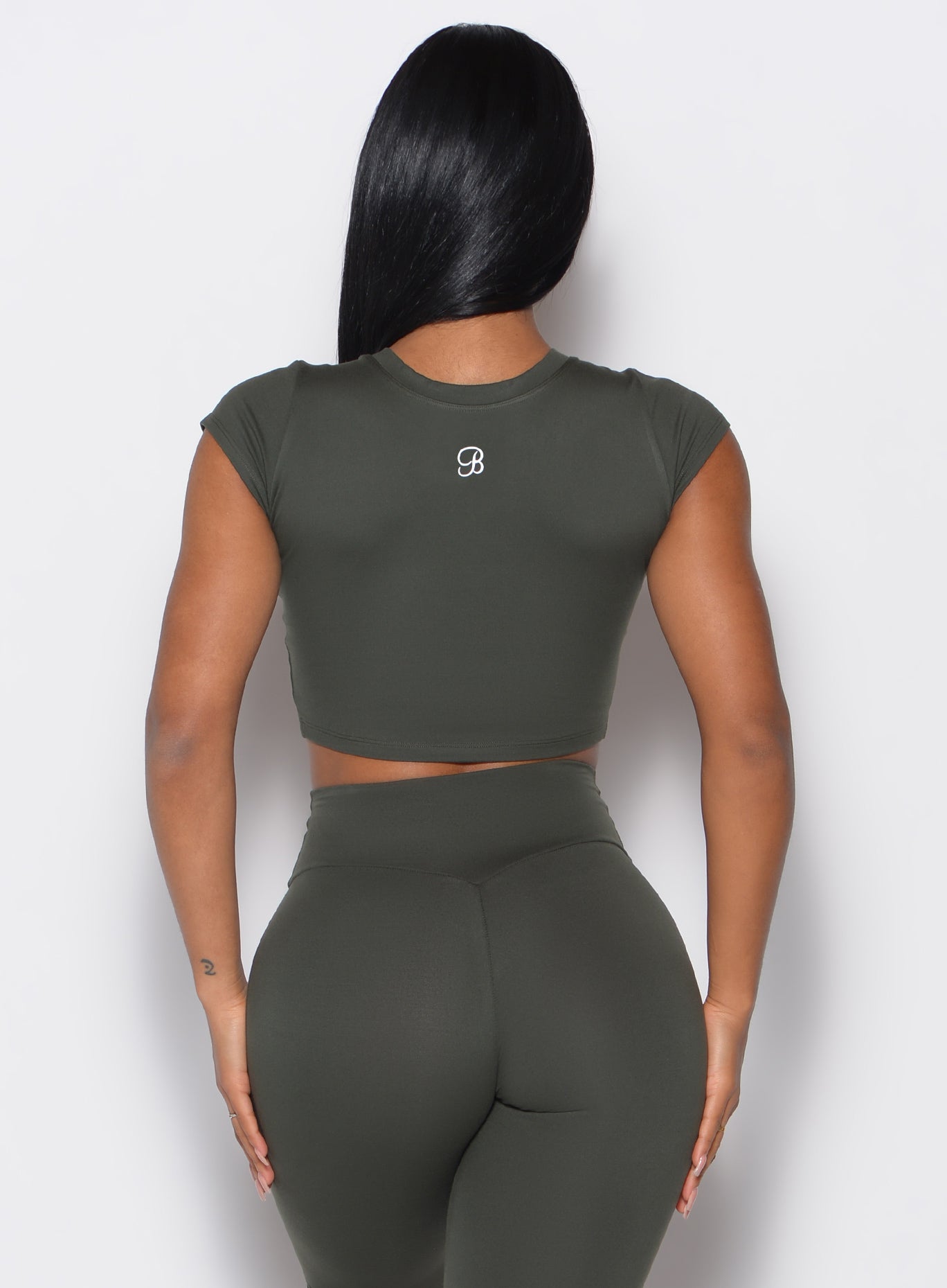 Back side close up view of a model wearing the Fit Fam Active Tee and the matching leggings in Deep Ivy color