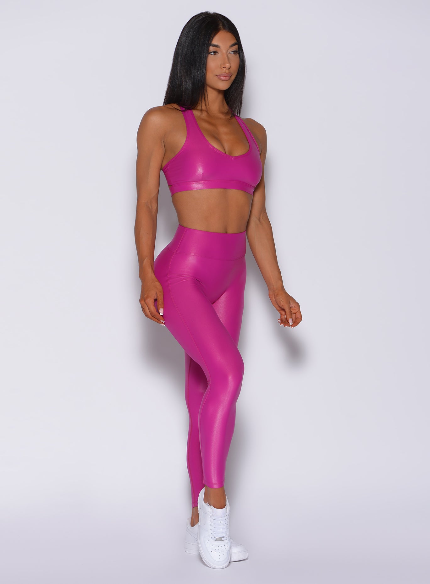 Right side profile view of a model angled right wearing our gloss pink leggings and a matching bra