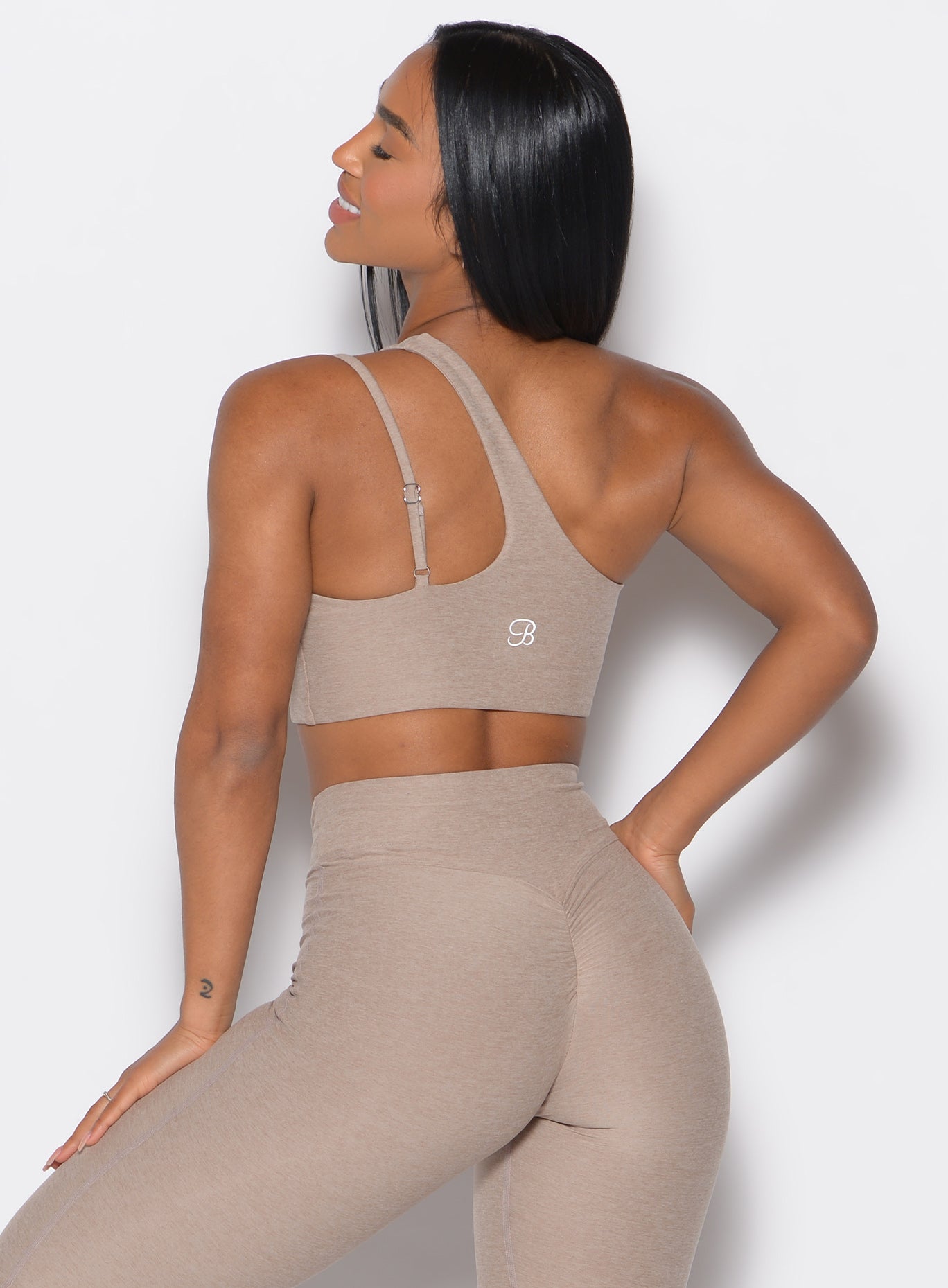 back profile of a model wearing the Lateral Top and the matching leggings in Desert Taupe color