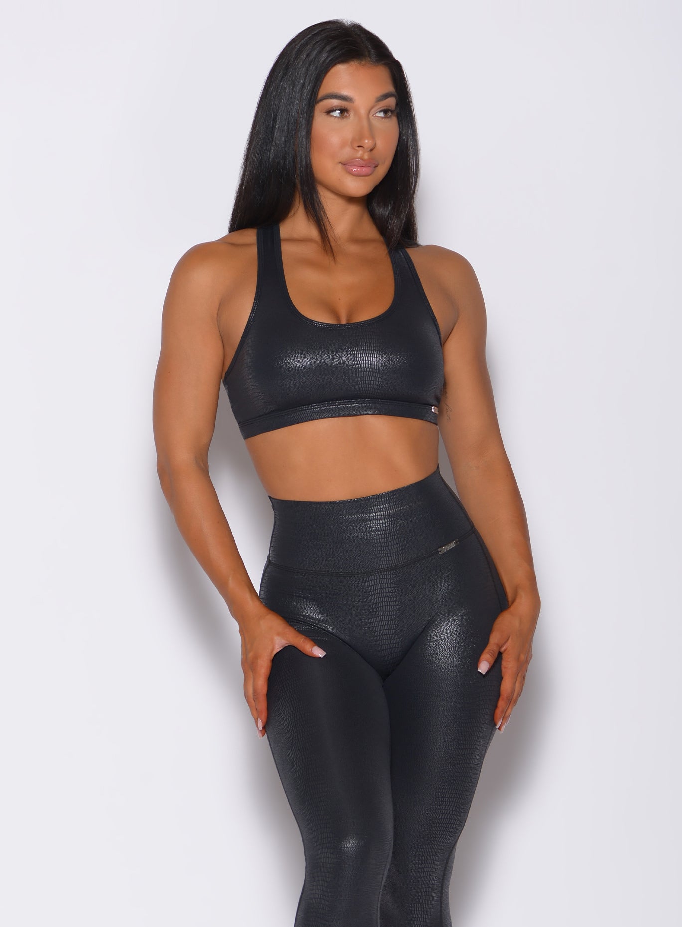 Front profile view of a model wearing our shine sports bra in black python color and a matching high waisted leggings