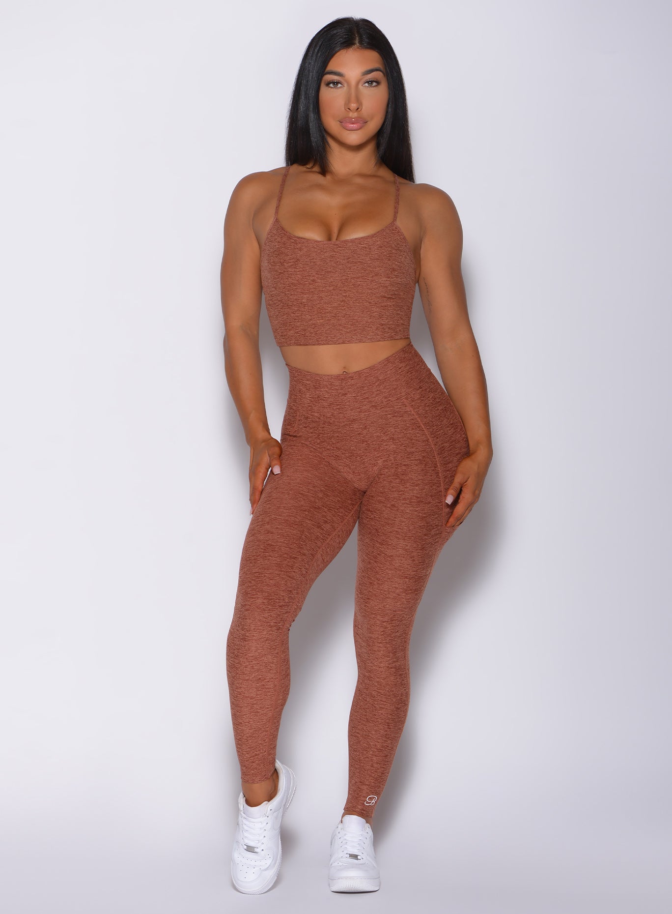 Front profile view of a model in our uplift pocket leggings in spiced chai color and a matching bra