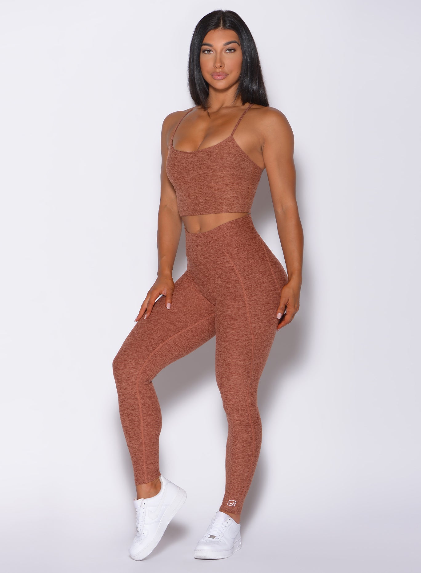 Front profile view of a model facing forward wearing  our uplift pocket leggings in spiced chai color and a matching bra