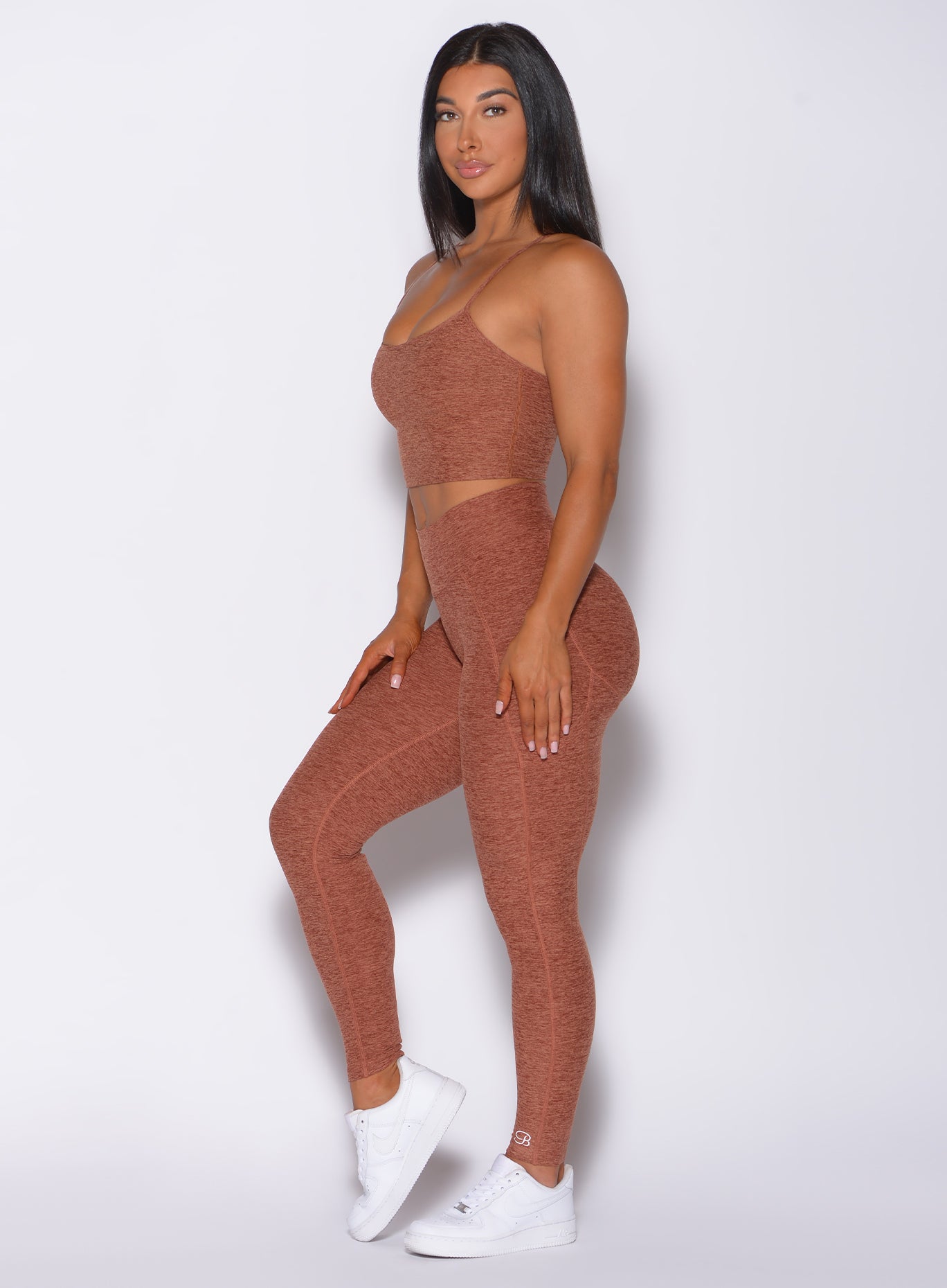 Left side profile view of a model in our uplift pocket leggings in spiced chai color and a matching bra