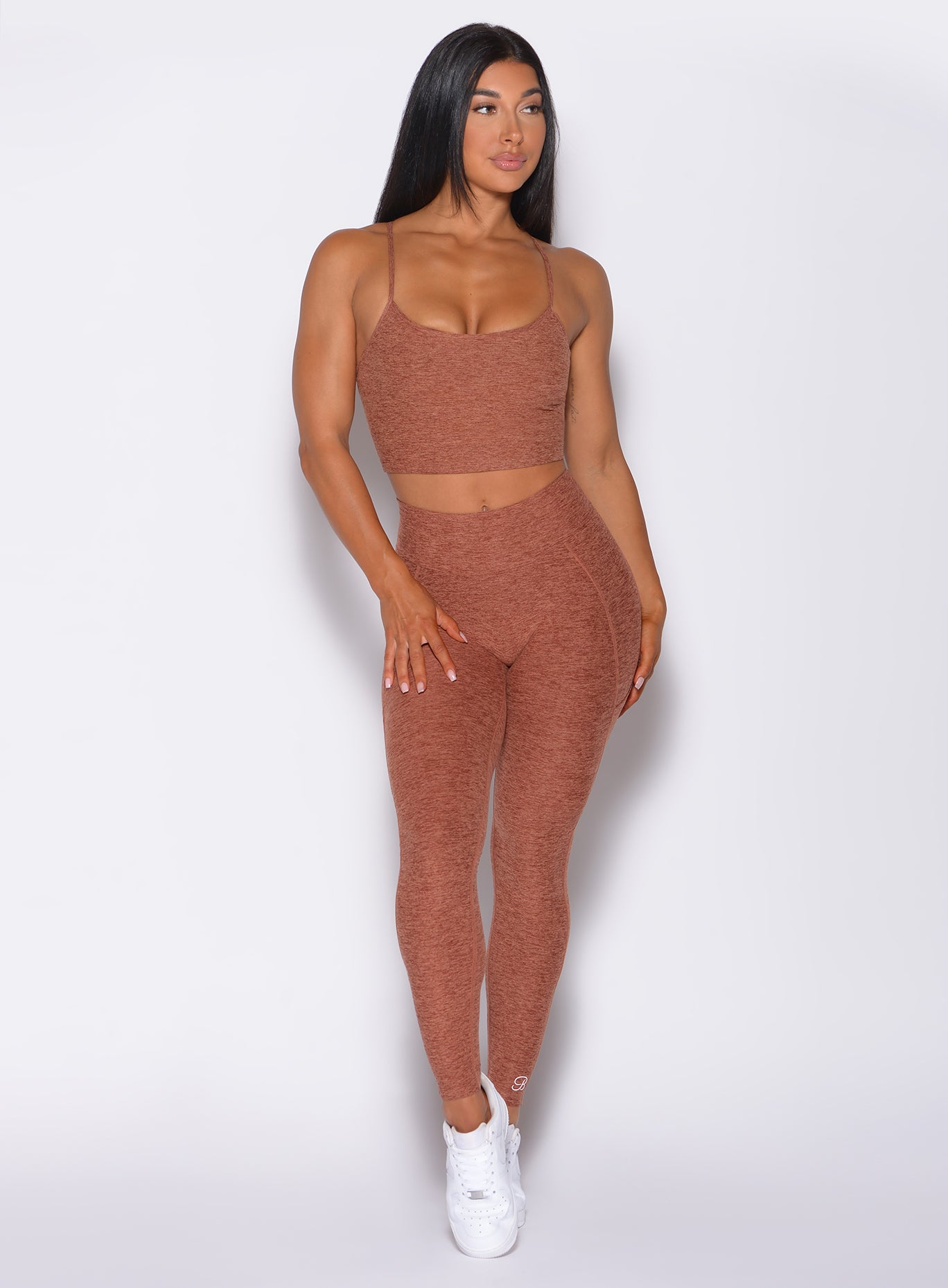 Front profile view of a model wearing our uplift pocket leggings in spiced chai color and a matching sports bra