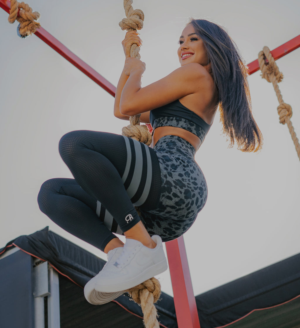 Model posing in the Charcoal Leopard Scrunch Thigh High and the matching bra hanging from a rope